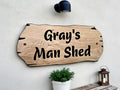 Man shed personalised oak sign mounted on exterior wall with plant decor