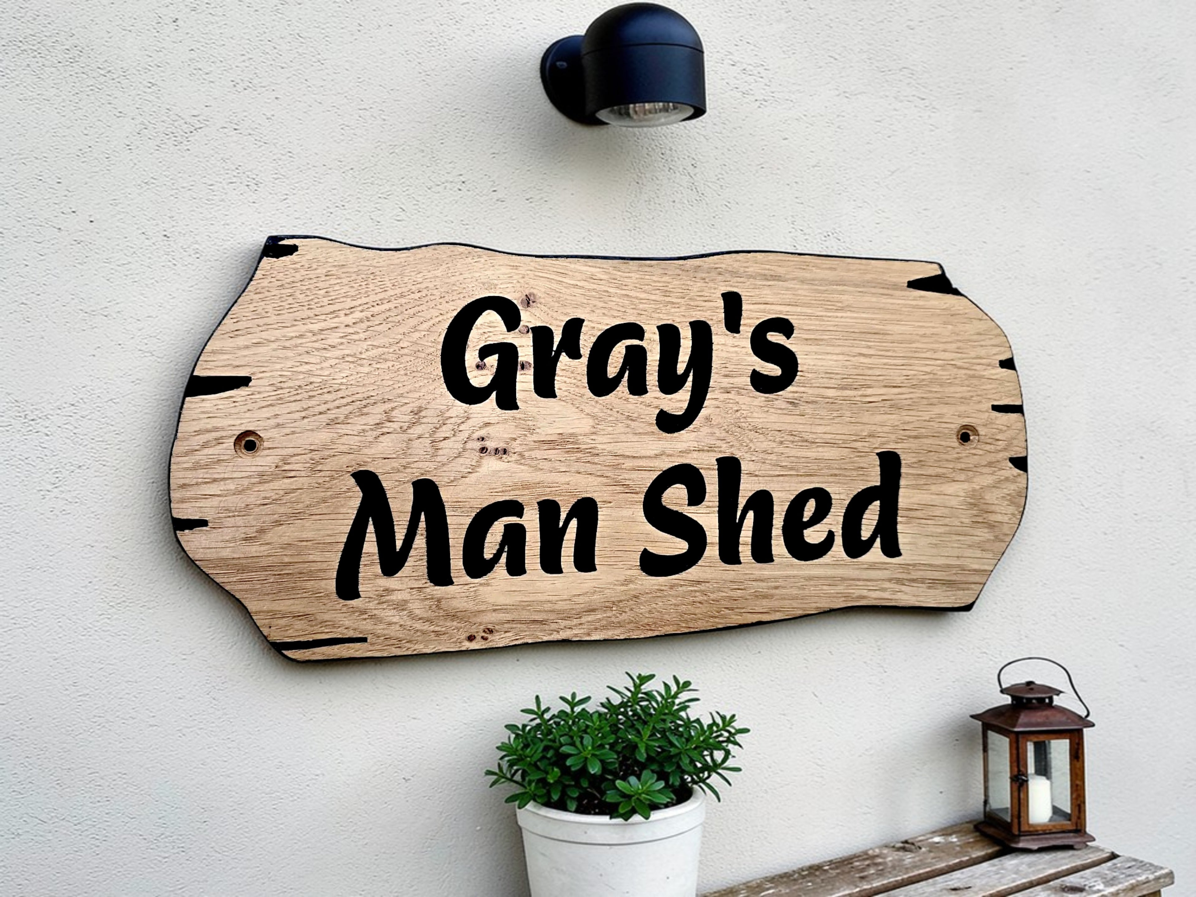 Man shed personalised oak sign mounted on exterior wall with plant decor