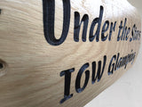 Wooden sign with engraved text 'Under the Stars IOW Glamping' on a white background Close up of deep  engraved lettering 