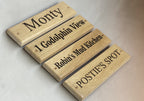 Four wooden signs with engraved names on a light background