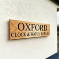 Personalised oak business sign mounted on exterior rendered wall in the UK