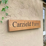 Custom oak farmhouse sign on textured exterior wall with ivy detail