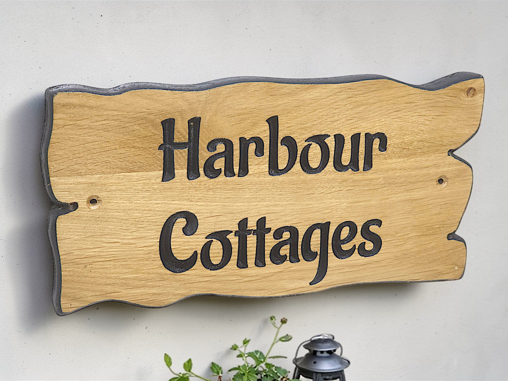 Large personalised oak house name sign Harbour Cottages mounted above bench with lantern and plant