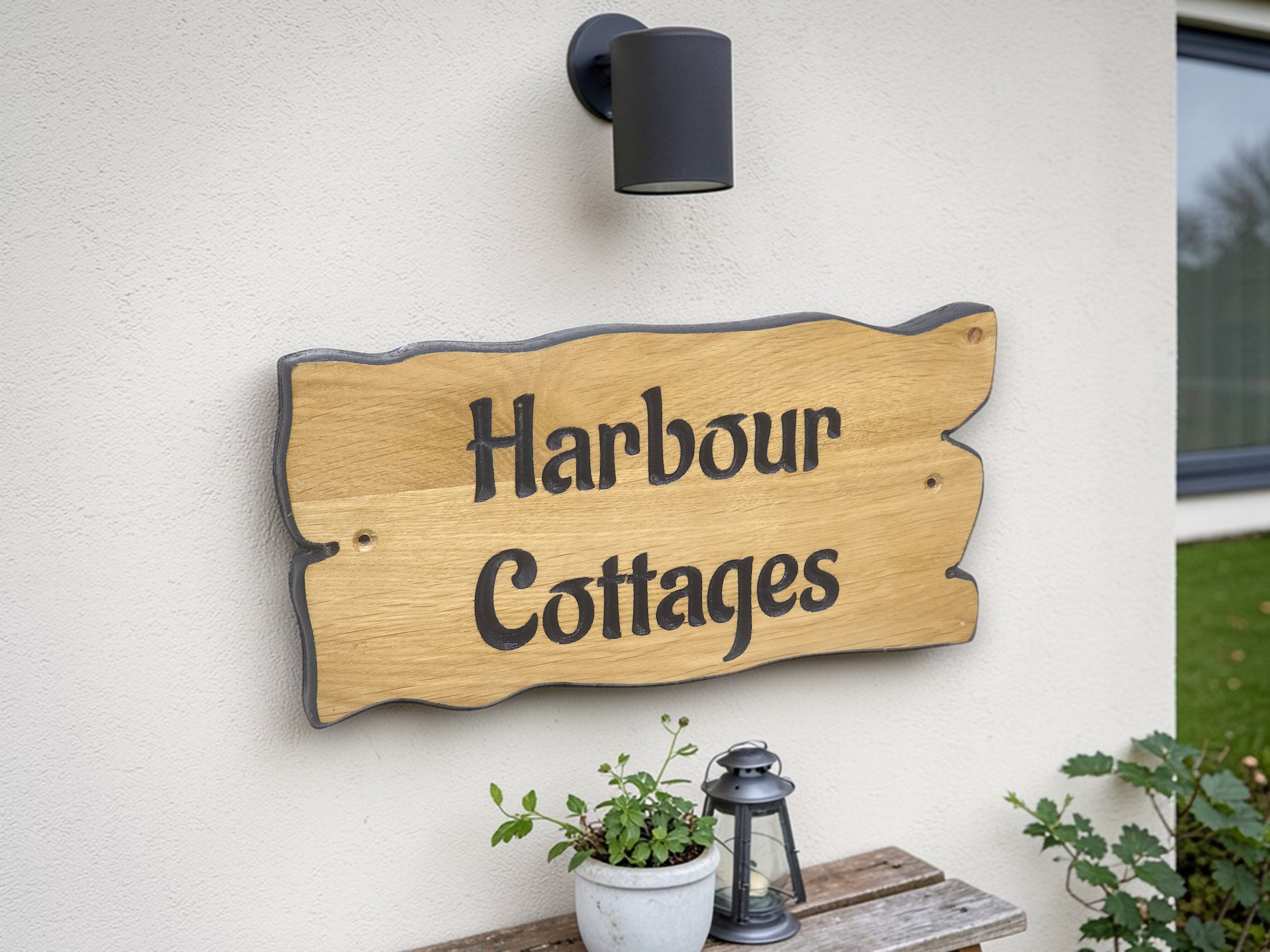 Wooden sign with 'Harbour Cottages' on a wall outside a building.