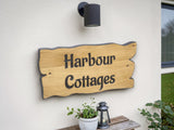 Wooden sign with 'Harbour Cottages' on a wall outside a building.