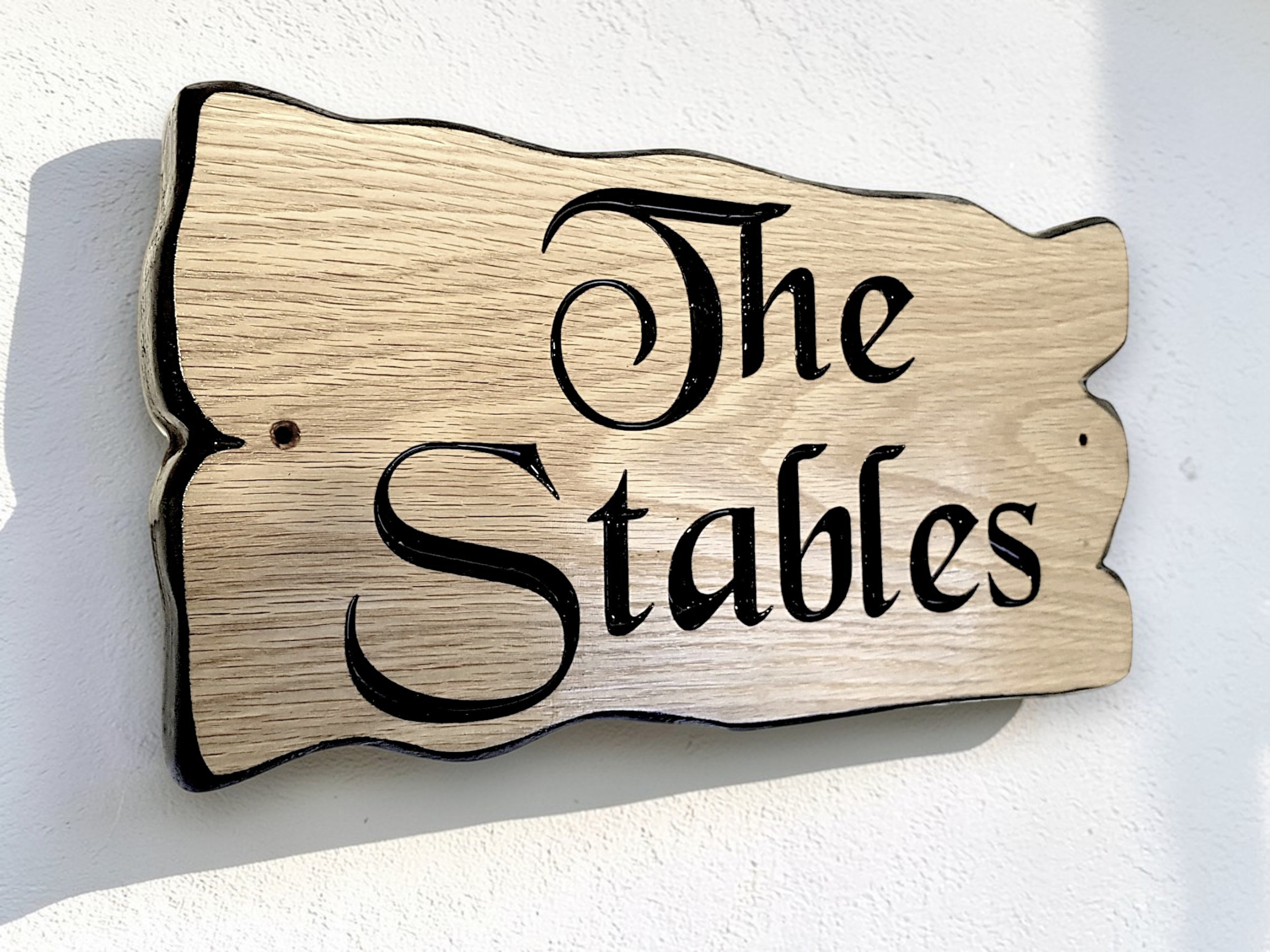 Custom engraved oak house sign The Stables mounted on exterior wall, rustic wooden name plaque