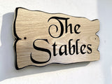 Custom engraved oak house sign The Stables mounted on exterior wall, rustic wooden name plaque