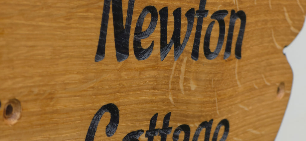 Close-up of engraved personalised solid oak cottage sign showing natural wood grain and precision laser engraving