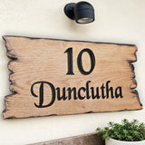 Wooden house number sign with '10 Dunclutha' on a white wall.