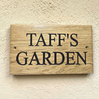 Personalised oak garden sign with deep engraved lettering mounted on exterior wall