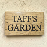 Personalised oak garden sign with deep engraved lettering mounted on exterior wall