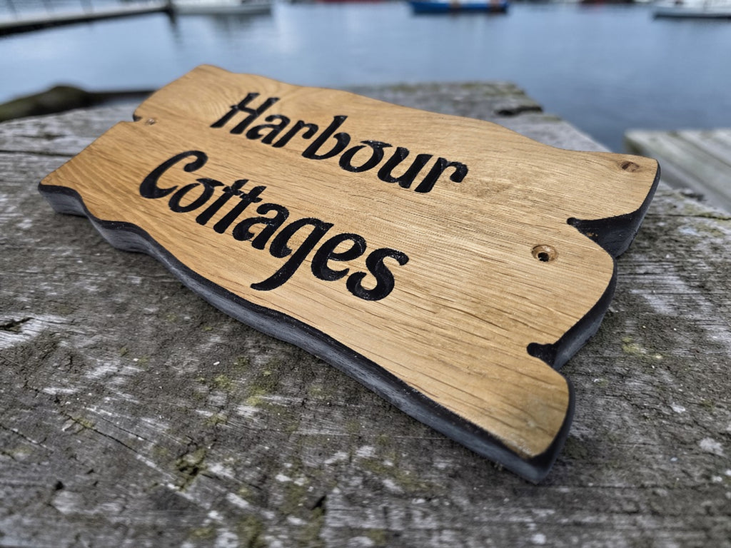Close up detail of engraved oak house sign showing wood grain and black painted lettering finish