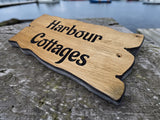 Close up detail of engraved oak house sign showing wood grain and black painted lettering finish