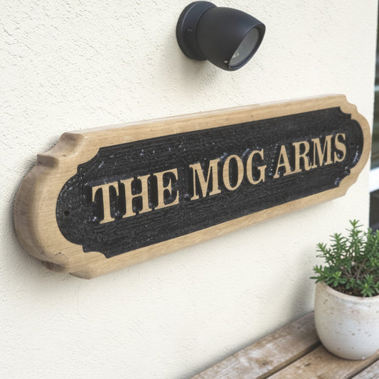 Angled view of personalised solid oak house name sign mounted on exterior wall