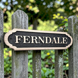 Rustic outdoor wooden house sign mounted on garden fence