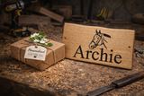 Personalised oak animal name plaque displayed on rustic woodworking bench, gift idea