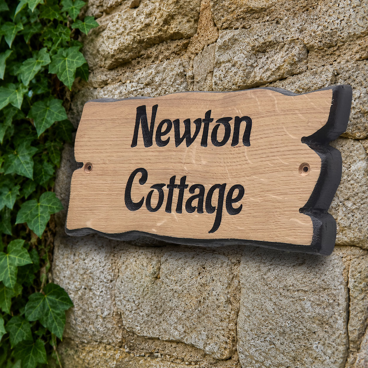 Side view of engraved solid oak cottage name plaque showing natural live edge profile
