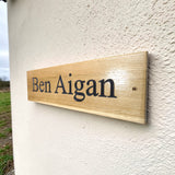 Custom oak house name sign with engraved text mounted on farmhouse wall