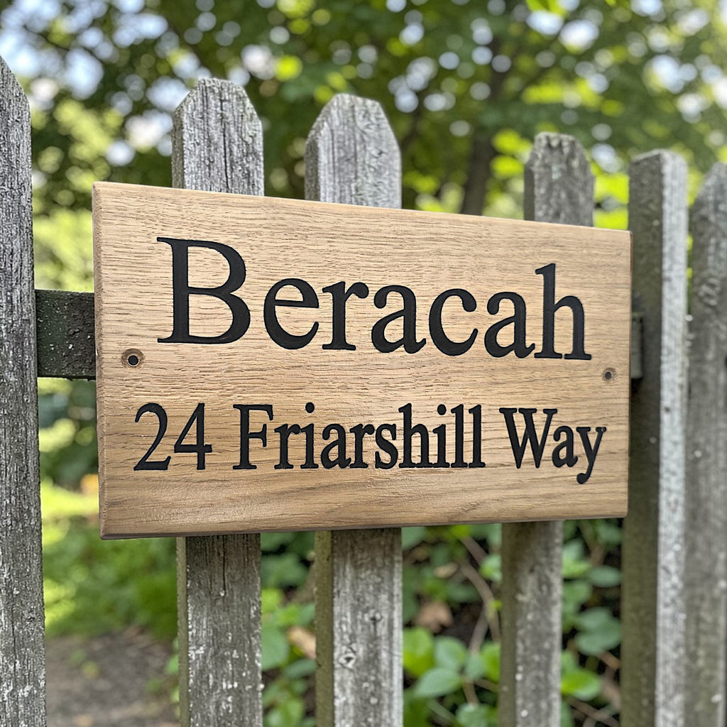 Custom engraved oak house sign mounted on wooden garden fence