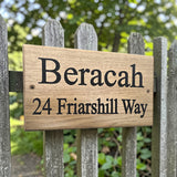Custom engraved oak house sign mounted on wooden garden fence